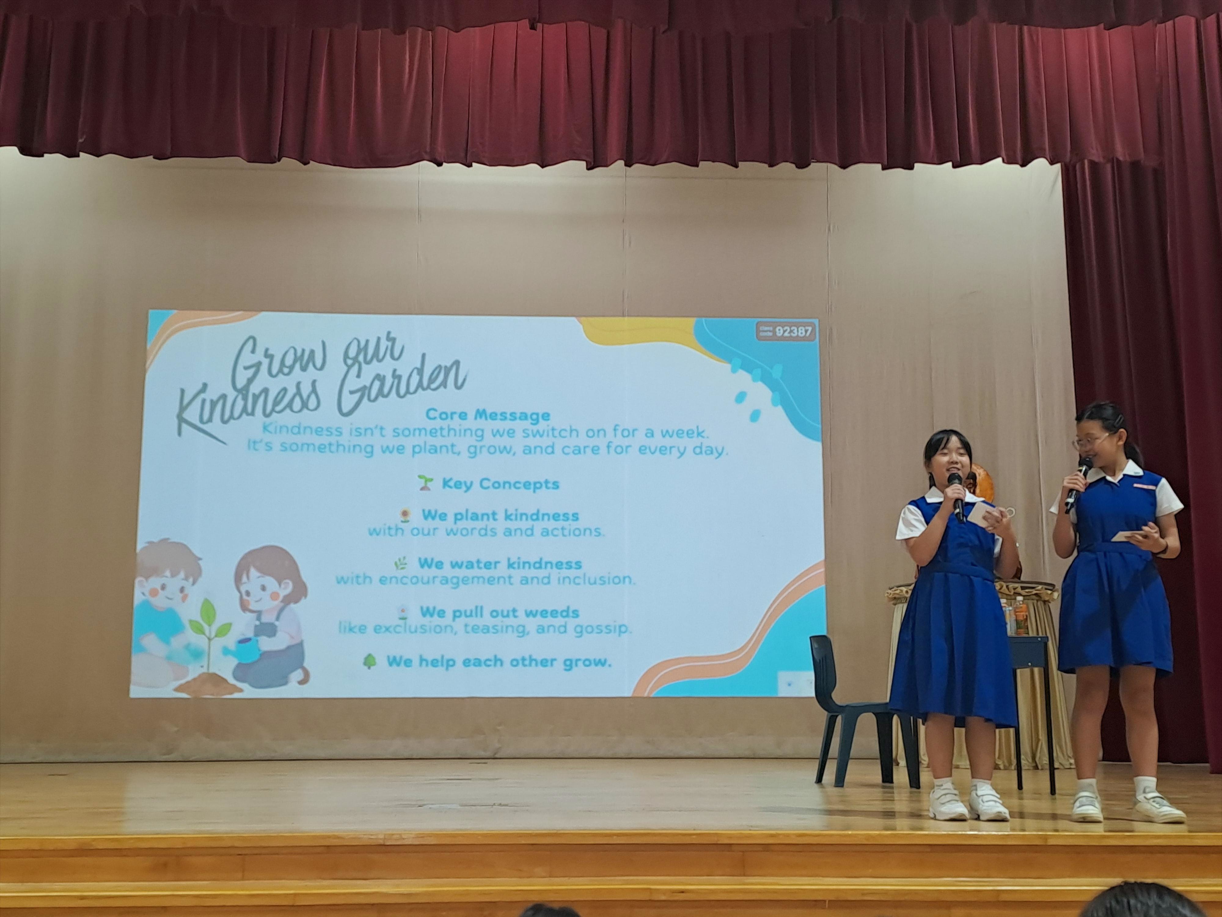 Pupils in school uniform facilitating on stage on ‘Grow our Kindness Garden.'